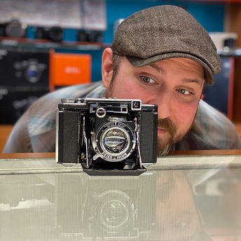 Man looking at vintage camera on display theshutterbug staff Gabe