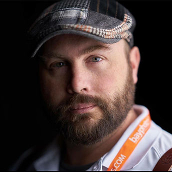 Bearded man wearing a hat looking at the camera with theshutterbug staff sean