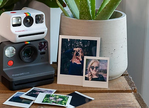 Two Polaroid cameras and photos on wood table, theshutterbug